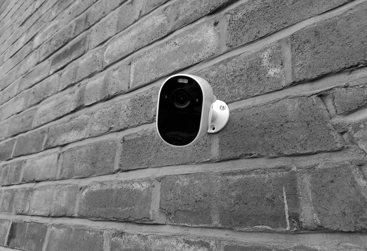services-04 Close-up of a security camera mounted on a brick wall in monochrome.