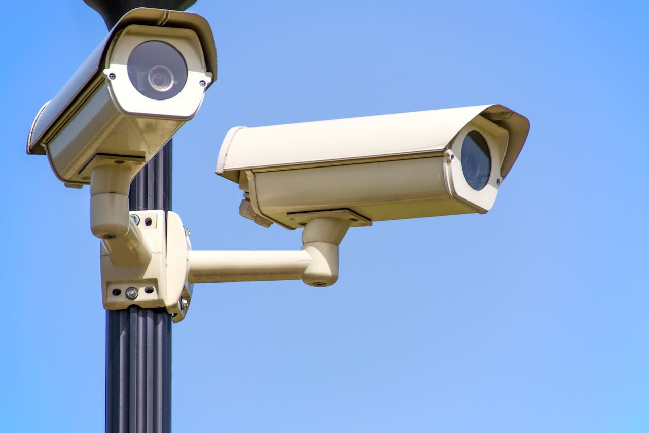 who-we-are Outdoor security cameras mounted on a pole against a clear blue sky, ensuring vigilant surveillance.